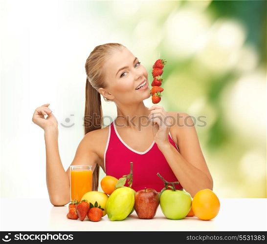 fitness, diet and food concept - young woman with organic food or fruits eating strawberry
