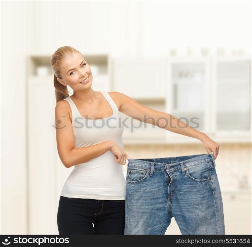 fitness, diet and good shape concept - sporty woman showing big pants