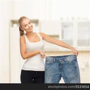 fitness, diet and good shape concept - sporty woman showing big pants