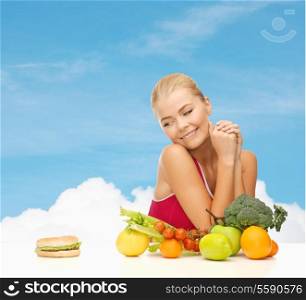 fitness, diet and healthcare concept - doubting woman with fruits and hamburger