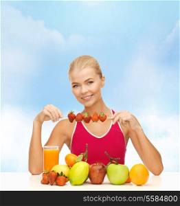 fitness, diet and healthcare concept - smiling young woman with organic food on the table and strawberries