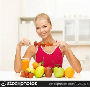 fitness, diet and healthcare concept - smiling young woman with organic food on the table and strawberries