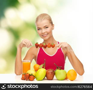 fitness, diet and healthcare concept - smiling young woman with organic food on the table and strawberries