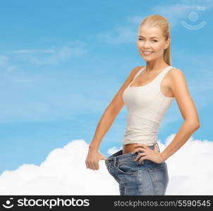 fitness, diet and healthcare concept - sporty woman showing big pants