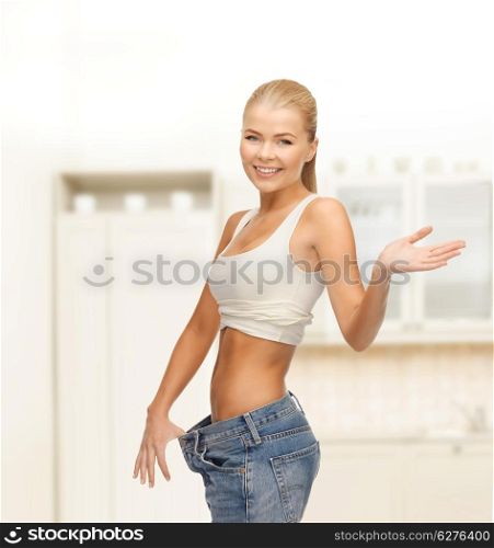 fitness, diet and healthcare concept - sporty woman showing big pants