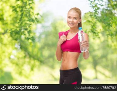 fitness, diet and people concept - happy smiling sporty woman with bottle of water and towel over green natural background. sporty woman with bottle of water and towel