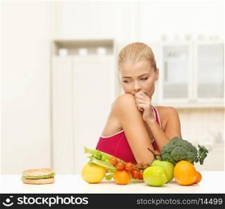 fitness, diet, health and food concept - doubting woman with fruits and hamburger