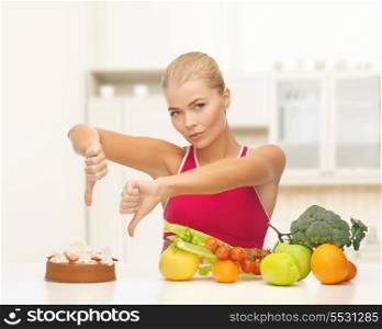 fitness, diet, health and food concept - upset woman with healthy food showing thumbs down to cake