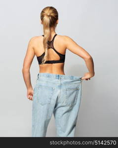 fitness, diet, weight loss and people concept - young slim sporty woman in oversize pants. young slim sporty woman in oversize pants