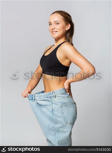 fitness, diet, weight loss and people concept - young slim sporty woman in oversize pants. young slim sporty woman in oversize pants