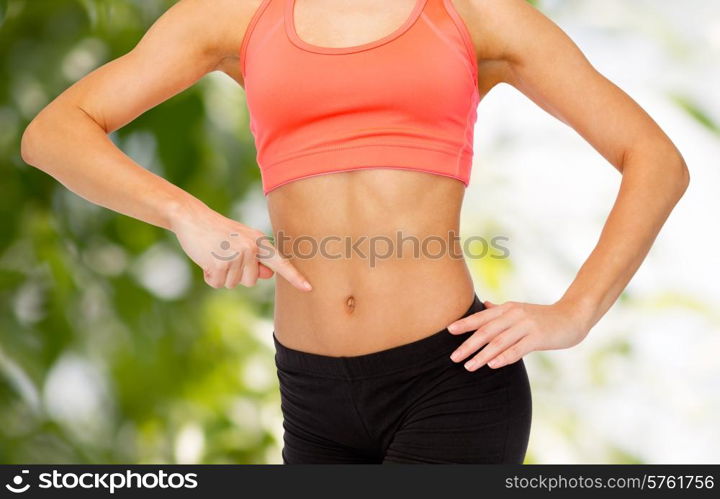 fitness, exercise and diet concept - close up of woman pointing finger at her six pack