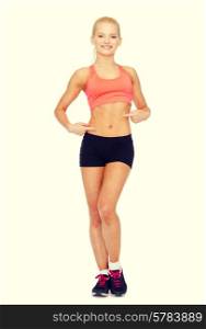 fitness, exercise and diet concept - smiling beautiful sporty woman pointing at her six pack