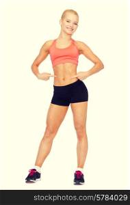 fitness, exercise and diet concept - smiling beautiful sporty woman pointing at her six pack