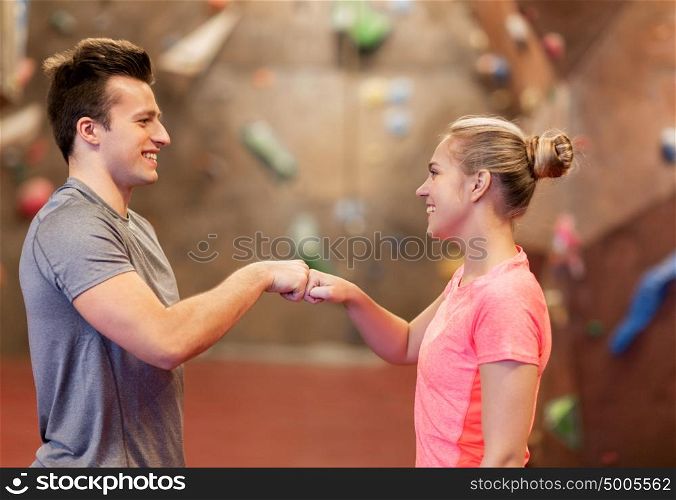 fitness, extreme sport, bouldering, people and healthy lifestyle concept - man and woman exercising at indoor climbing gym making fist bump gesture. man and woman exercising at indoor climbing gym