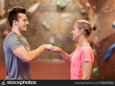 fitness, extreme sport, bouldering, people and healthy lifestyle concept - man and woman exercising at indoor climbing gym making fist bump gesture. man and woman exercising at indoor climbing gym