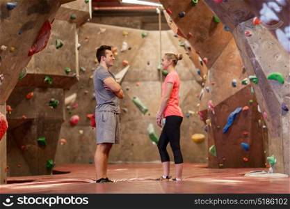 fitness, extreme sport, bouldering, people and healthy lifestyle concept - man and woman talking at indoor climbing gym. man and woman talking at indoor climbing gym
