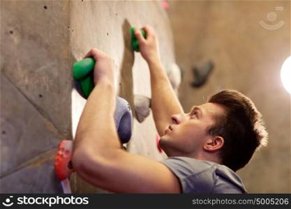 fitness, extreme sport, bouldering, people and healthy lifestyle concept - young man exercising at indoor climbing gym wall. young man exercising at indoor climbing gym wall
