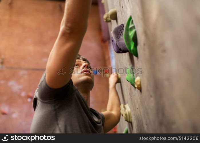 fitness, extreme sport, bouldering, people and healthy lifestyle concept - young man exercising at indoor climbing gym. young man exercising at indoor climbing gym