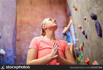 fitness, extreme sport, bouldering, people and healthy lifestyle concept - young woman exercising at indoor climbing gym wall. young woman exercising at indoor climbing gym wall