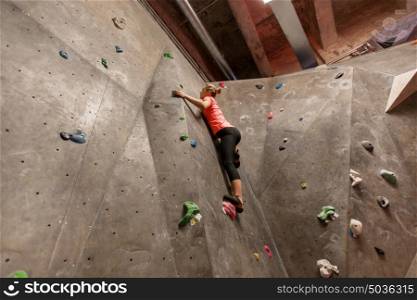 fitness, extreme sport, bouldering, people and healthy lifestyle concept - young woman exercising at indoor climbing gym. young woman exercising at indoor climbing gym