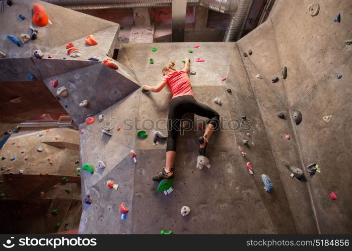fitness, extreme sport, bouldering, people and healthy lifestyle concept - young woman exercising at indoor climbing gym. young woman exercising at indoor climbing gym