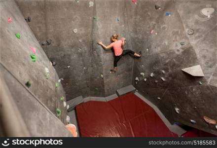 fitness, extreme sport, bouldering, people and healthy lifestyle concept - young woman exercising at indoor climbing gym wall. young woman exercising at indoor climbing gym wall