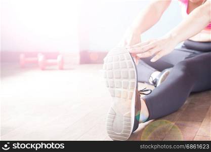 Fitness female in black pants and sneaker stretching after workout with copy space