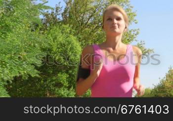 Fitness female runner in sporty pink top jogging in the park