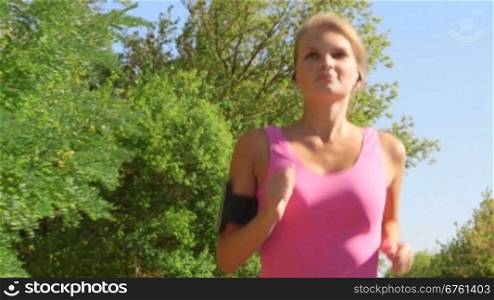 Fitness female runner in sporty pink top jogging in the park