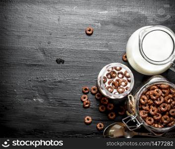 Fitness food. Chocolate flakes with milk. On a black wooden background.. Fitness food. Chocolate flakes with milk.