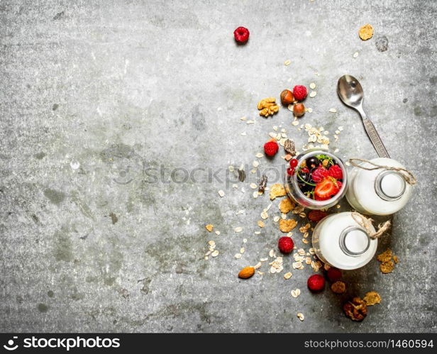 Fitness food. Muesli with berries, nuts and milk in bottles. On the stone table.. Fitness food. Muesli with berries, nuts and milk in bottles.