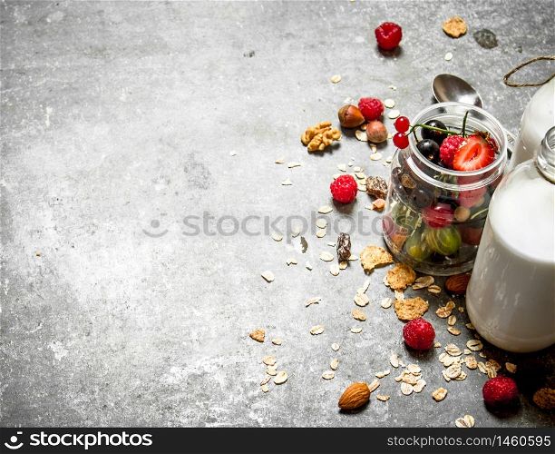Fitness food. Muesli with berries, nuts and milk in bottles. On the stone table.. Fitness food. Muesli with berries, nuts and milk in bottles.