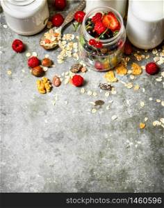 Fitness food. Muesli with berries, nuts and milk in bottles. On the stone table.. Fitness food. Muesli with berries, nuts and milk in bottles.