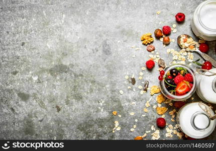 Fitness food. Muesli with berries, nuts and milk in bottles. On the stone table.. Fitness food. Muesli with berries, nuts and milk in bottles.