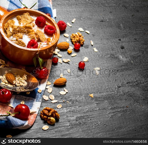 Fitness food. Muesli with berries, nuts and milk in the bowl. On a black wooden background.. Muesli with berries, nuts and milk in the bowl.