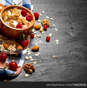 Fitness food. Muesli with berries, nuts and milk in the bowl. On a black wooden background.. Muesli with berries, nuts and milk in the bowl.