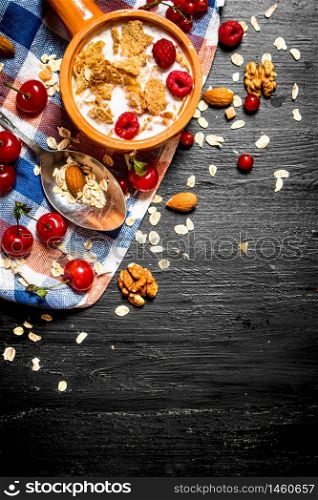 Fitness food. Muesli with berries, nuts and milk in the bowl. On a black wooden background.. Muesli with berries, nuts and milk in the bowl.