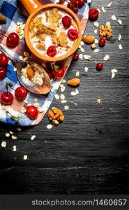 Fitness food. Muesli with berries, nuts and milk in the bowl. On a black wooden background.. Muesli with berries, nuts and milk in the bowl.
