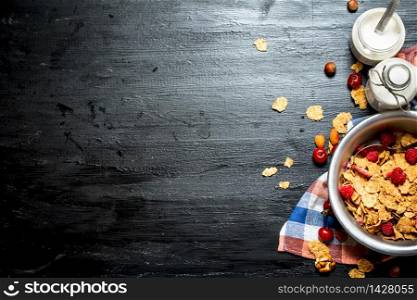 Fitness food. Muesli with ripe berries and milk. On a black wooden background.. Fitness food. Muesli with ripe berries and milk.