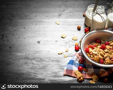 Fitness food. Muesli with ripe berries and milk. On a black wooden background.. Fitness food. Muesli with ripe berries and milk.