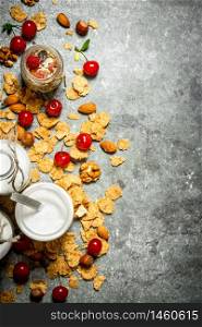 Fitness food. Muesli with wild berries and milk in bottles. On the stone table.. Fitness food. Muesli with wild berries and milk in bottles.