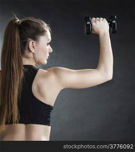 Fitness girl fit woman lifting dumbbells weights doing exercise with dumb bells training shoulder muscles back view gray background