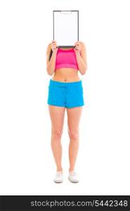 Fitness girl holding blank clipboard in front of her face isolated on white&#xA;