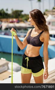 Fitness girl in sportswear outfit working out with a elastic band on waterfront harbour.. Fitness woman in sportswear outfit working out with a elastic band on waterfront harbour.