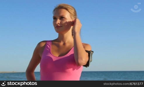 Fitness girl runner using wireless headset to listen music while exercising outdoors