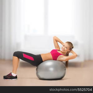 fitness, gym, exercise and health concept - young woman doing exercise on fitness ball at home