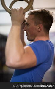 Fitness handsome man doing dipping exercise using rings in the gym