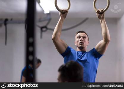 Fitness handsome man doing dipping exercise using rings in the gym