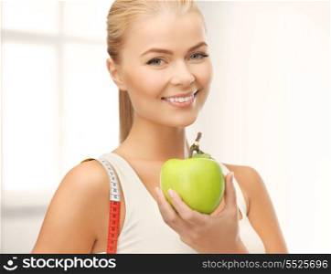 fitness, health and diet concept - beautiful sporty woman with apple and measuring tape