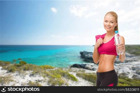 fitness, healthcare and dieting concept - smiling sporty woman with bottle of water and towel